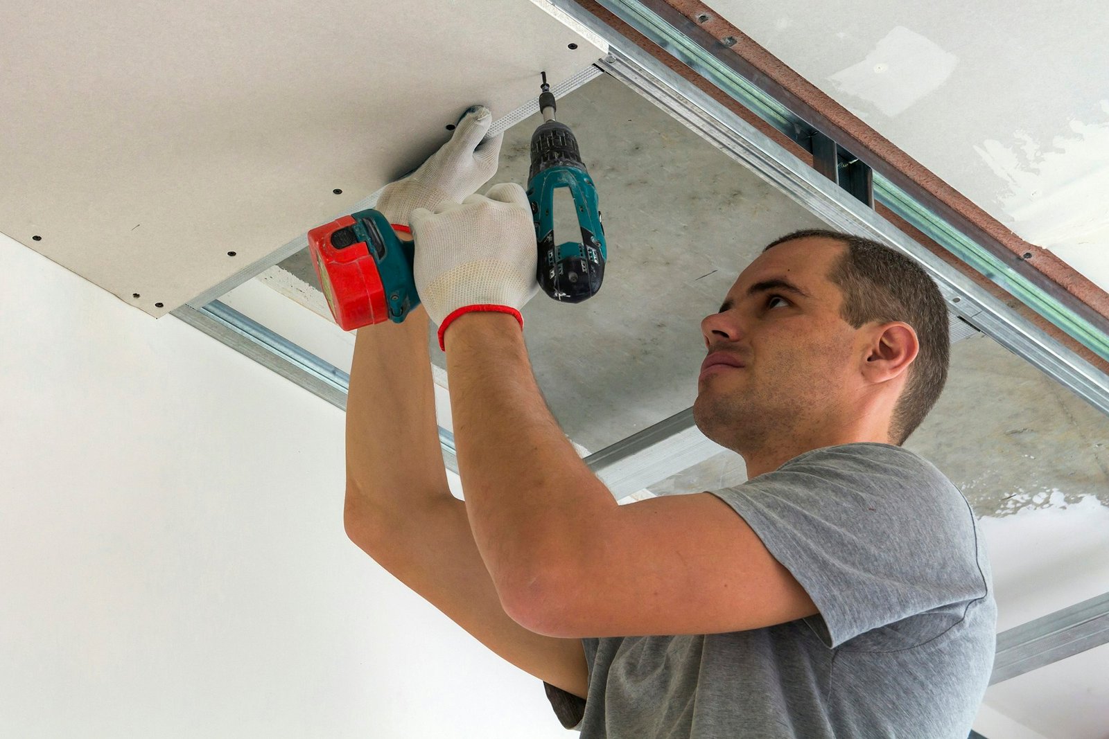 Construction worker assemble a suspended ceiling with drywall and fixing the drywall